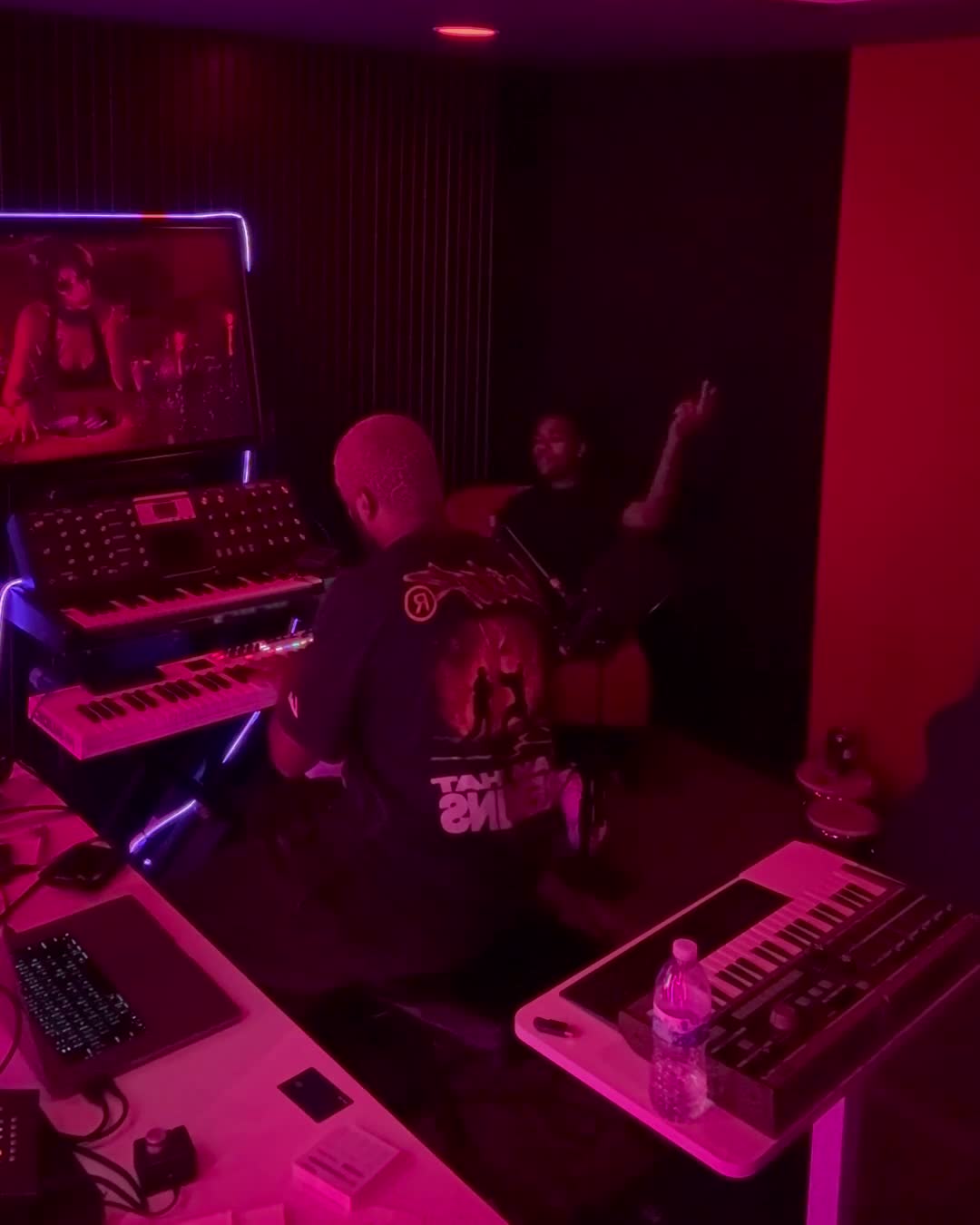 merchant and a collaborator working in a studio surrounded by keyboards